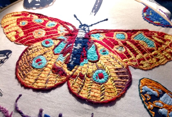 Bayeux Stitch Peacock Butterfly. Wool on linen tea-towel. Renata Bursten.